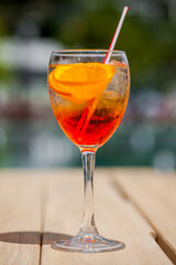 A cocktail with ice, an orange and a straw