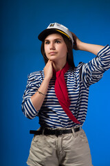A young, attractive girl with long, straight hair, brown eyes in a vest, a captain's cap and a red...