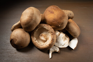 Multiple fresh shiitake mushrooms on wooden board