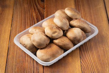 Multiple fresh shiitake mushrooms on wooden board