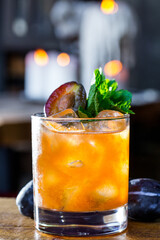 A cocktail with plums, mint and ice