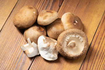Multiple fresh shiitake mushrooms on wooden board