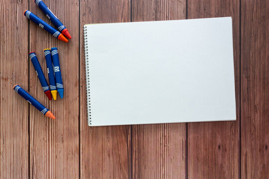 Blank sketchbook with colorful crayon for kids on wooden table