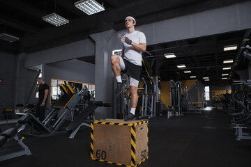 Fototapeta na wymiar Full length shot of a sportsman stepping on a box, doing functional training routine at gym