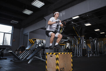 Young male athlete jumping on a box at functional training gym