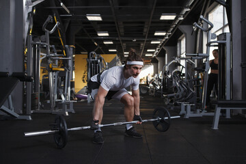 Fototapeta na wymiar Focused male athlete doing deadlift exercise with barbell