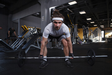 Fototapeta na wymiar Sportsman looking focused, lifting heavy barbell at the gym