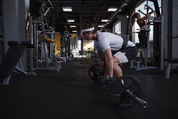 Fototapeta na wymiar Strong athletic man exercising with barbell at functional training gym