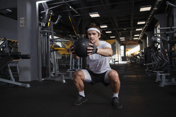Fototapeta na wymiar Full length shot of a sportsman doing squats with medicine ball