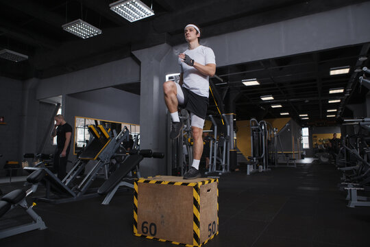 Full length shot of a sportsman stepping on a box, doing functional training routine at gym