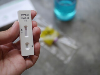 Close-up photo of hand holding Antigen test kit showing results of testing for COVID-19 test result is negative, with alcohol backdrop, ideal for illustrating COVID-19 news.