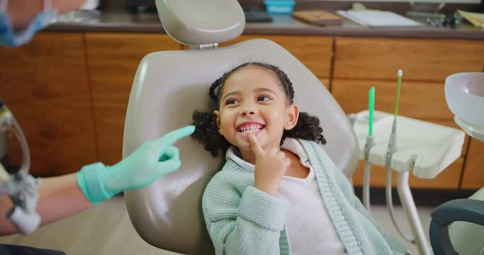Pediatric dentist bonding with child, explaining dental procedure by making it fun or playful during consult. Friendly, adorable little girl learning about healthy teeth and maintaining oral hygiene
