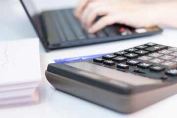 Woman are working and typing  with laptop on  at office with a calculator.