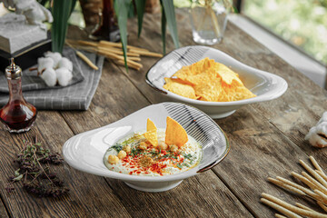 Portion of appetizers with hummus and nacho chips on wooden restaurant table