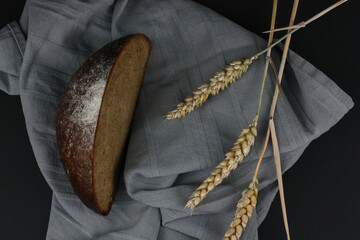 Close-up/Nahaufnahme von Brot mit Handtuch, Getreide und Mehl vor schwarzem Hintergrund
