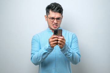 Young asian man feels angry looking at smartphone