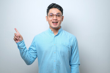 Young asian chinese man Surprised pointing with hand finger to the side, open mouth amazed...