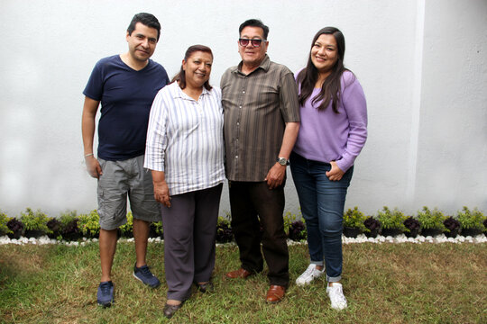 Latin family of parents and children pose for the photo as a family portrait in the garden outdoors enjoy quality time together and in harmony
