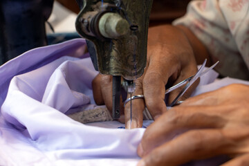 Embroidering Thai numbers on a student's shirt on an old sewing machine