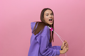 a funny, emotional woman stands in purple clothes and with white headphones around her neck...