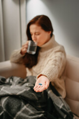 Hand with antibiotics of a blurred woman suffering from flu and infection. Cold seasonal disease concept.