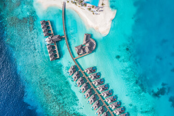 Aerial view of Maldives island, luxury travel water villas resort and wooden pier. Beautiful sky...
