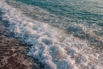 Landscape with stormy sea - waving water and foam - wave, covering sandy beach.