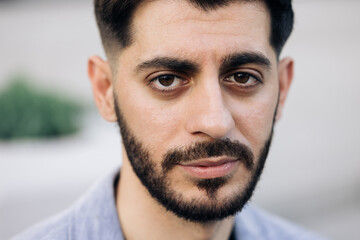 Obraz premium Face of serious bearded caucasian armenian young man looking at camera. Attractive guy stand on street city lifestyle. People. Beauty. Stand outdoors