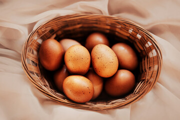 Beautiful chicken brown Easter eggs lie in a wooden wicker basket for Easter. Food for religious holidays.