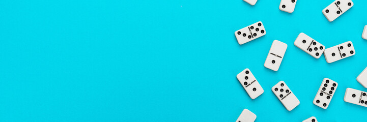 Domino pieces on turquoise blue background with copy space. Flat lay minimalist photo of some domino bones.