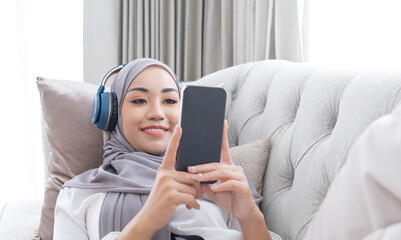 Close-up image, Attractive Muslim woman using a smartphone in living room, chatting with her...