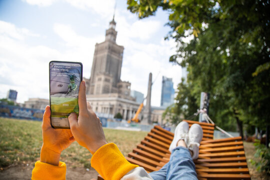 Warsaw, Poland - June 16, 2022: Young woman in front of Palace of Culture and Science using Vivus website (Soonly company) 