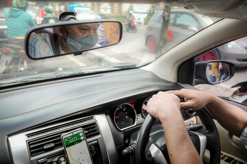 Adult Mature Asian Man Driving Car in a Busy City Street
