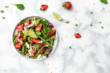 Healthy salad. green asparagus, strawberry, rocket and cottage cheese. Healthy balanced eating. Delicious balanced food concept, top view