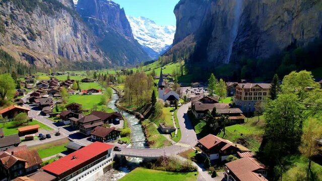 Scenic Lauterbrunnen village with Staubbach waterfall and snow-capped Swiss Alps. Traditional alpine landscape of Bernese Oberland, Switzerland.