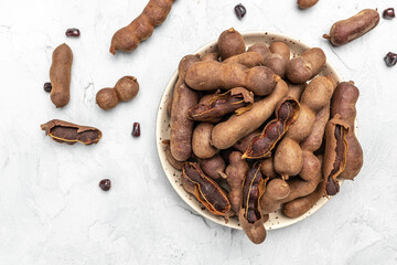 tamarinds beans in shell on a brown butchers block on a light background, healthy fruit. banner, menu, recipe place for text, top view