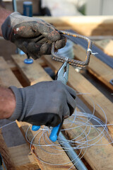 Close up photo of man holding pliers. Man works with reinforcement steel. Construction work in details.  