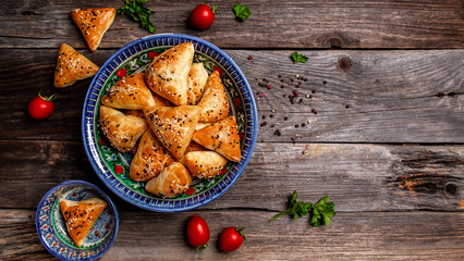 Obraz na płótnie Canvas Traditional Indian cuisine samosas baked pastry with savoury filling, popular Indian snacks with spices on rustic background, top view