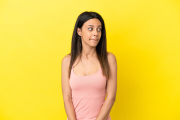 Obraz premium Young caucasian woman isolated on yellow background making doubts gesture looking side