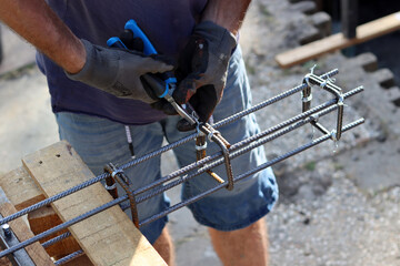 Close up photo of man holding pliers. Man works with reinforcement steel. Construction work in...