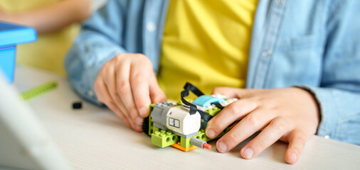 Programming work, learning robotics in elementary school. Children students assembly, launch, coding of robot. Constructor parts by instructions in tablet. STEM education science engineering class