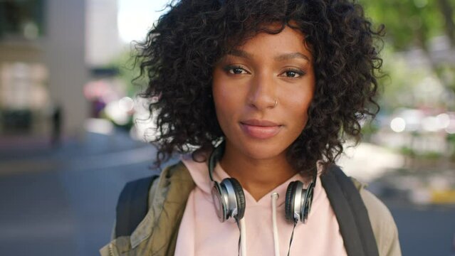 Portrait of a trendy young black woman with a carefree and cool attitude standing in the city. Beautiful, confident and confident african student with curly afro hair and headphones in the town