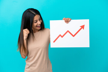 Young woman over isolated background holding a sign with a growing statistics arrow symbol and celebrating a victory