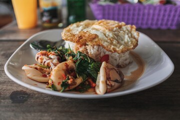 Thai Rice topped with stir-fried squid and basil with fried egg.