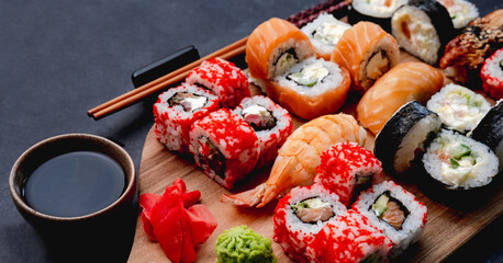 Colorful sushi maki set on wooden desk served with soy sauce and chopstick closeup. Oriental...