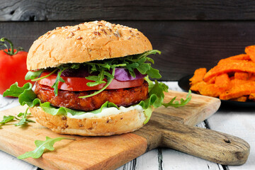 Plant based meatless burger of chickpeas and sweet potato. Side view against a rustic wood...