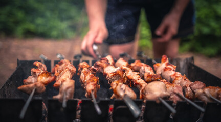 Man hands straighten the metal skewer with barbecue delicious grilled meat with smoke on brazier...