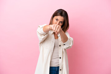 Middle age caucasian woman isolated on pink background with fighting gesture