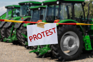 The inscription PROTEST on the background of tractors. Farmers protest symbol. - obrazy, fototapety, plakaty