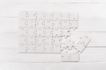 Small white puzzle sample on wooden table - obrazy, fototapety, plakaty